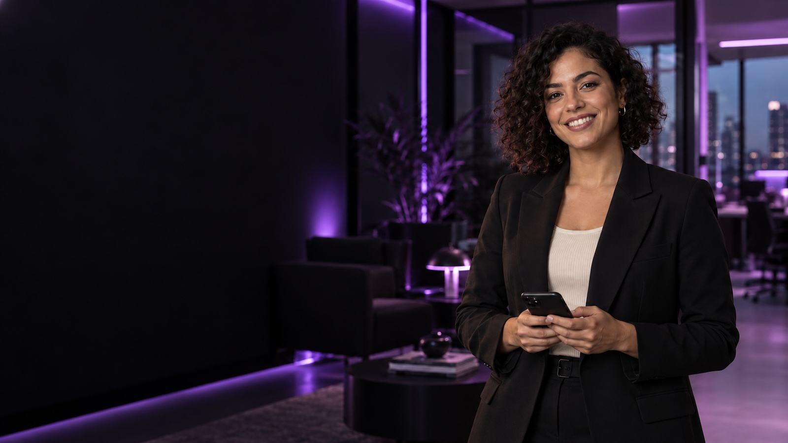 Mulher sorrindo e segurando um celular, em um escritório com iluminação violeta
